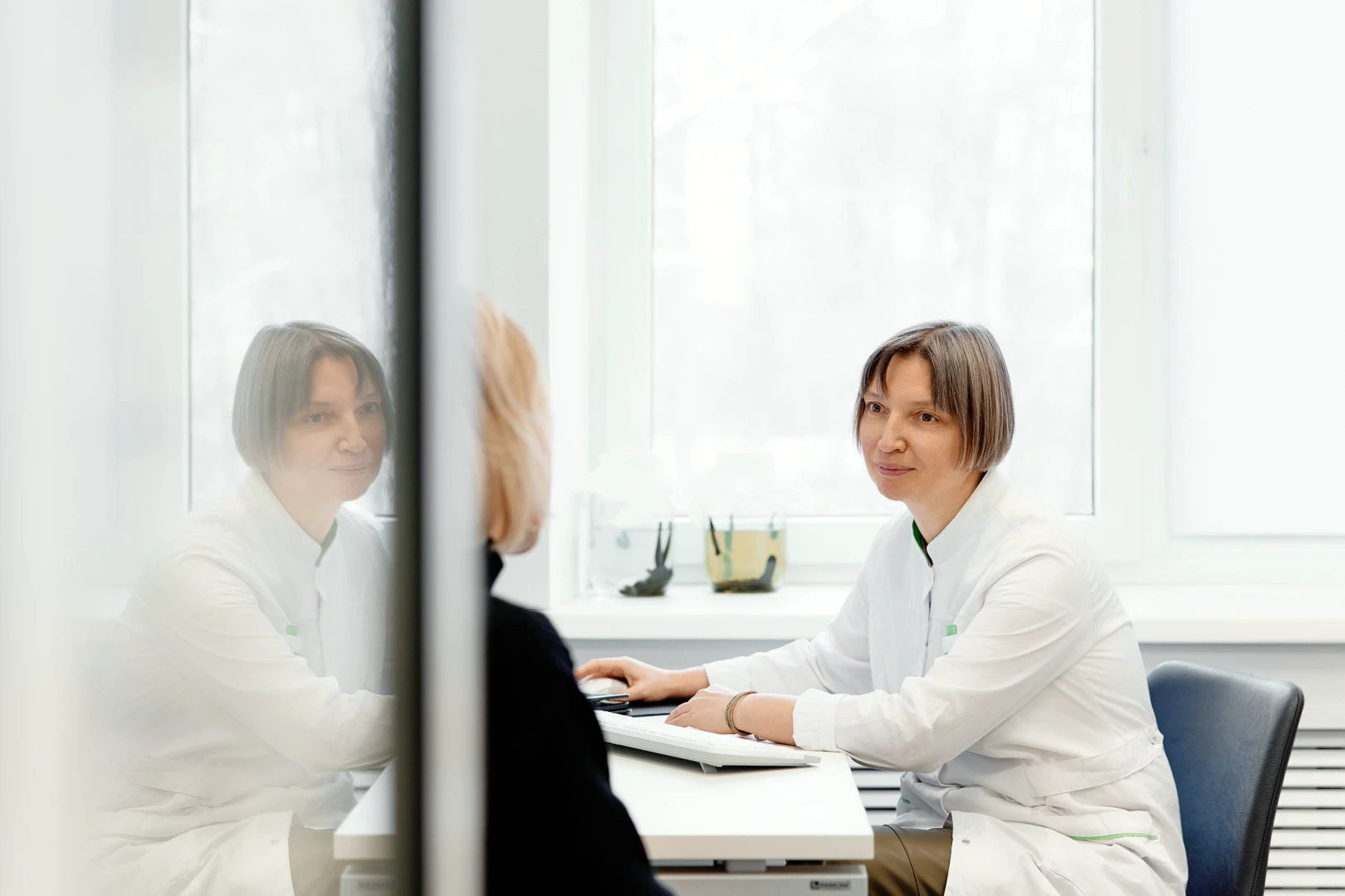 Иглорефлексотерапевт беседует с пациентом на приёме и проводит осмотр