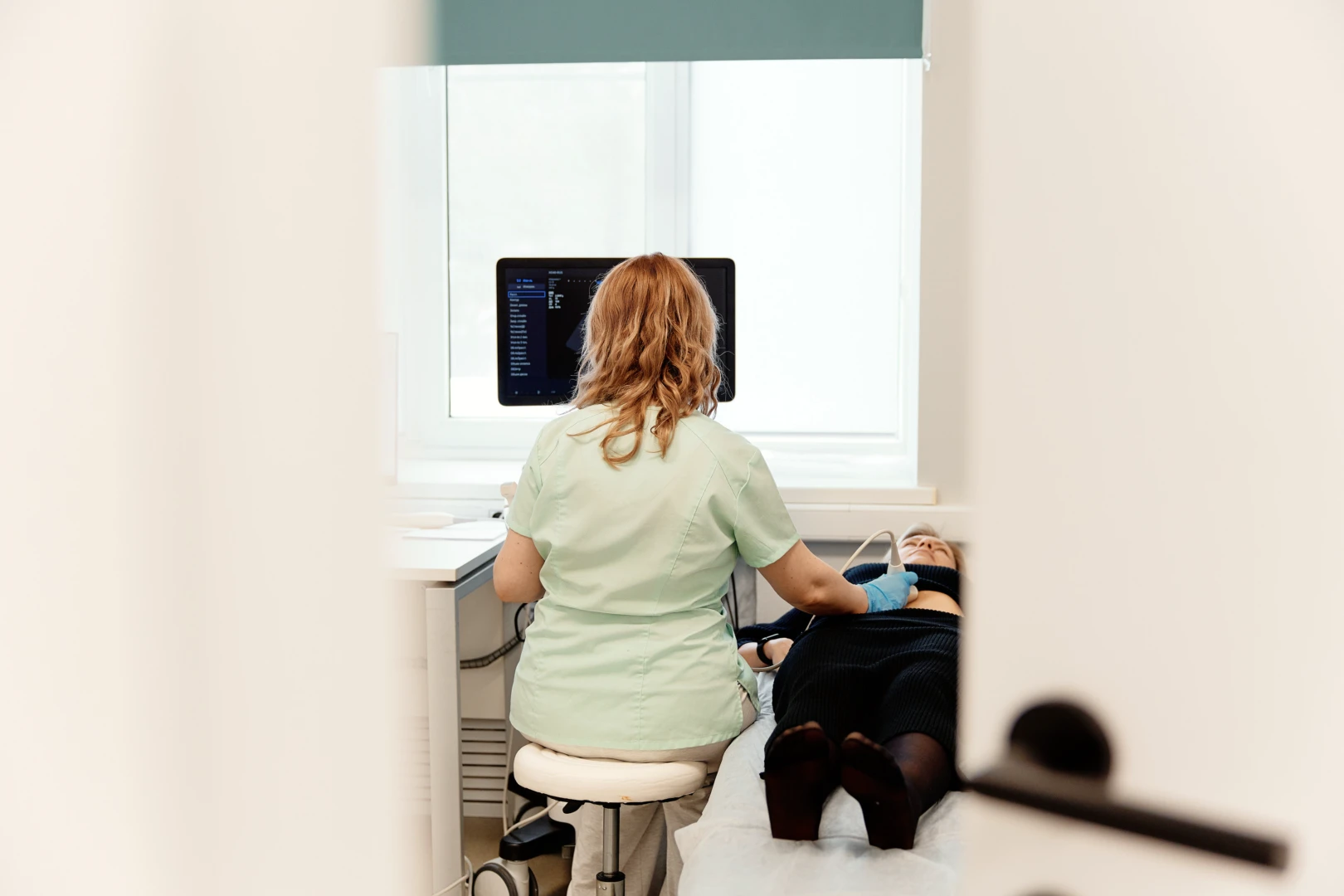 Женщина врач в белом халате объясняет результаты УЗИ сустава с эластометрией хряща пациентке.