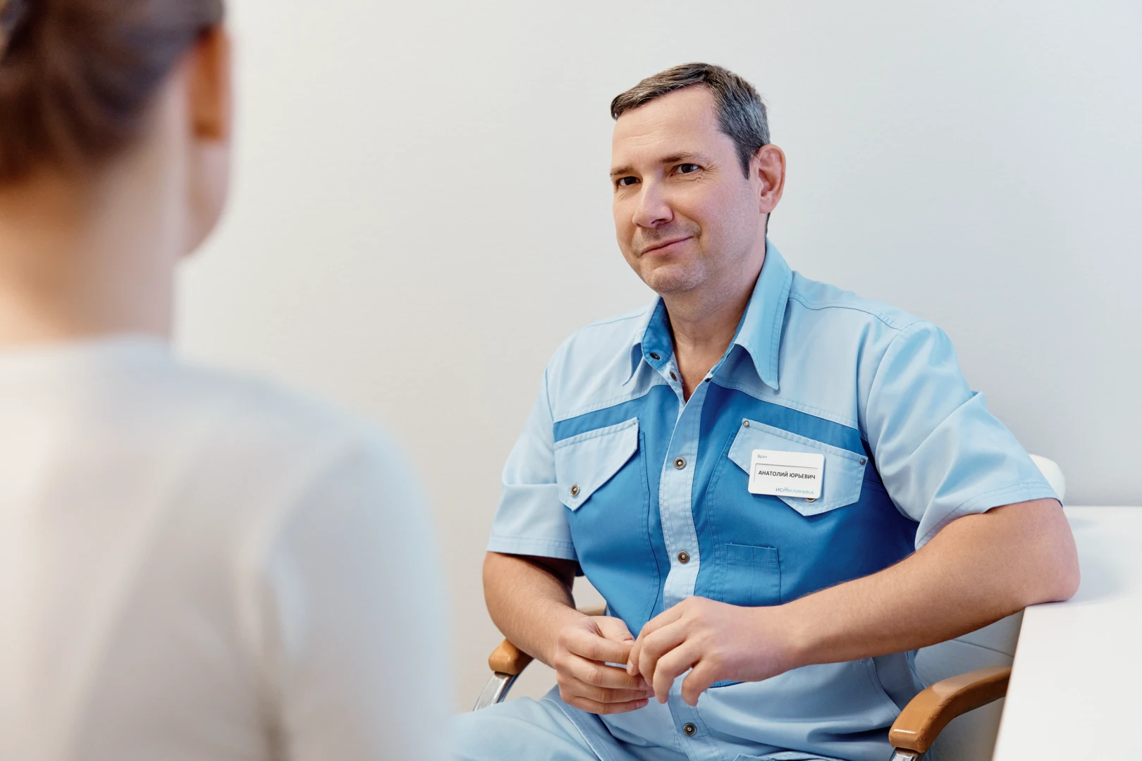 Женщина врач в белом халате беседует с пациенткой, обсуждая причины для визита.