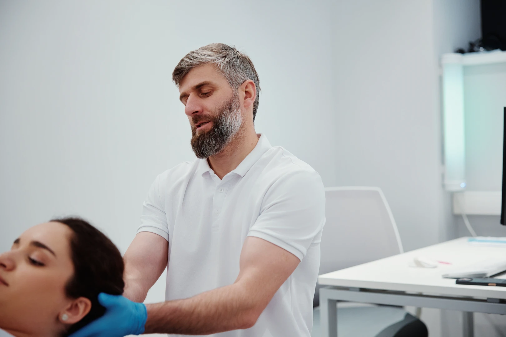 Невролог массирует болезненную зону головы пациента в Ист Клинике