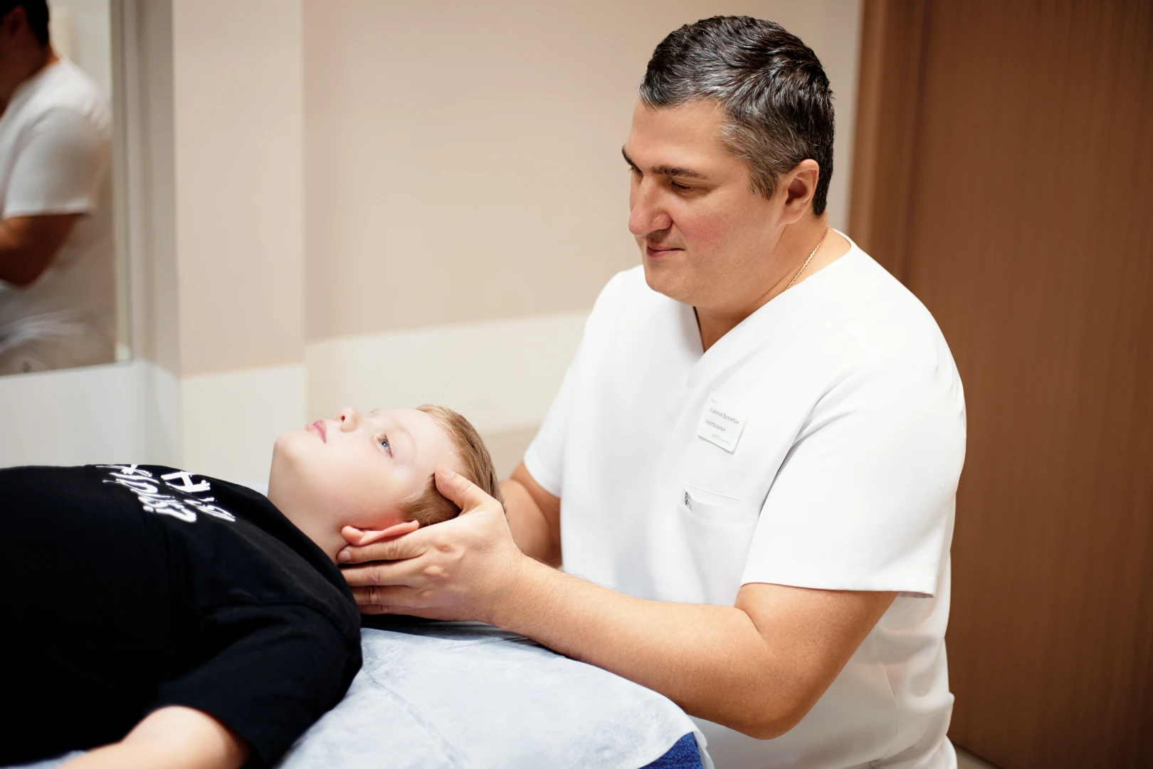 Врач проводит осмотр пациента на кинезиологическом сеансе