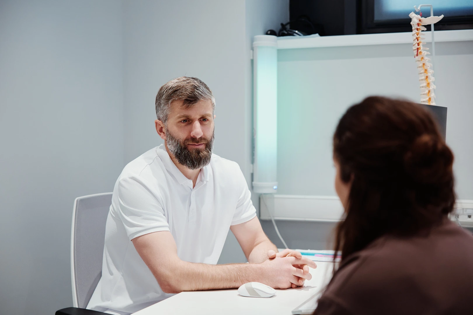 Остеопат беседует с пациентом на приёме перед проведением сеанса остеопрактики