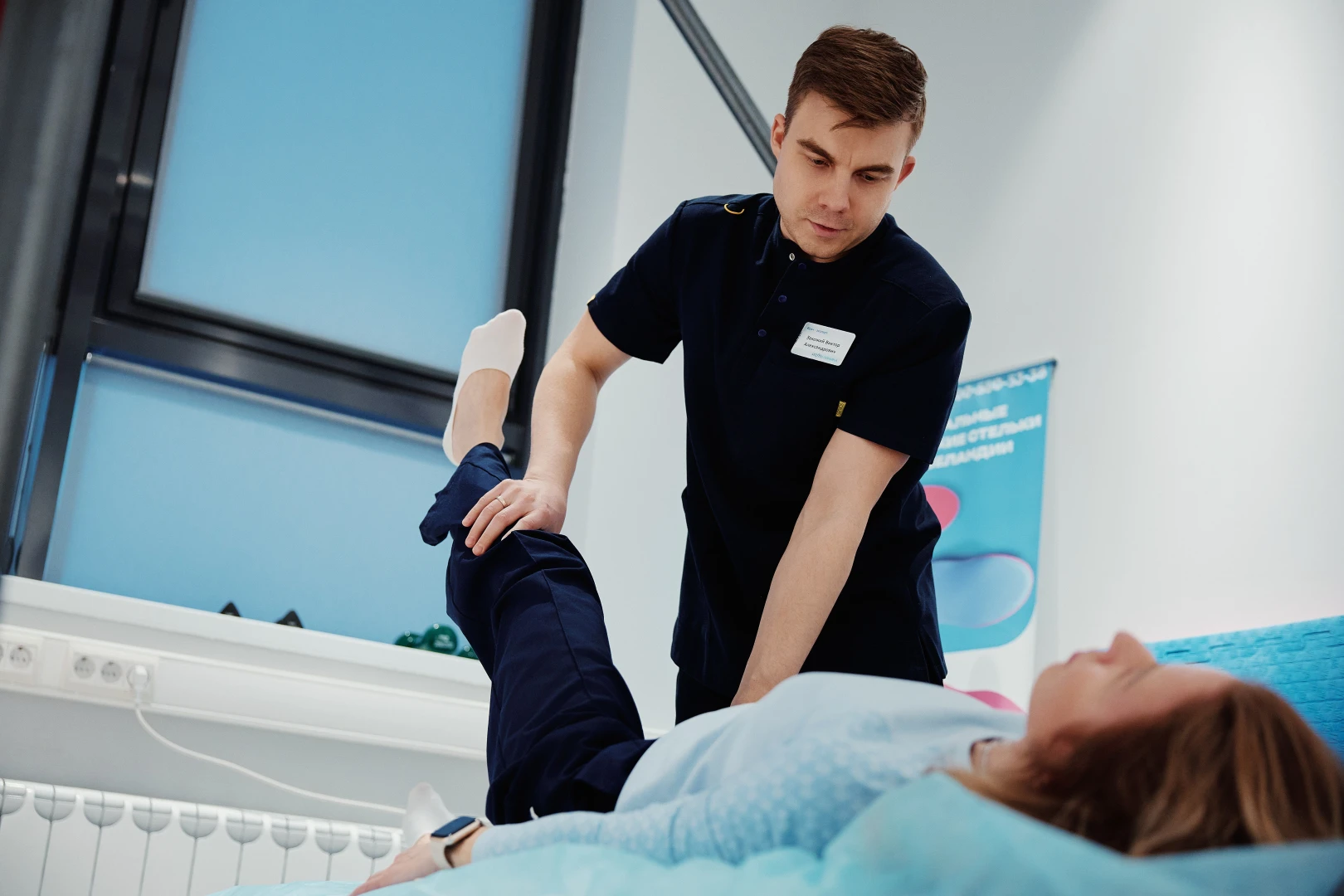 Кинезиолог проводит с пациентом сеанс и показывает упражнения