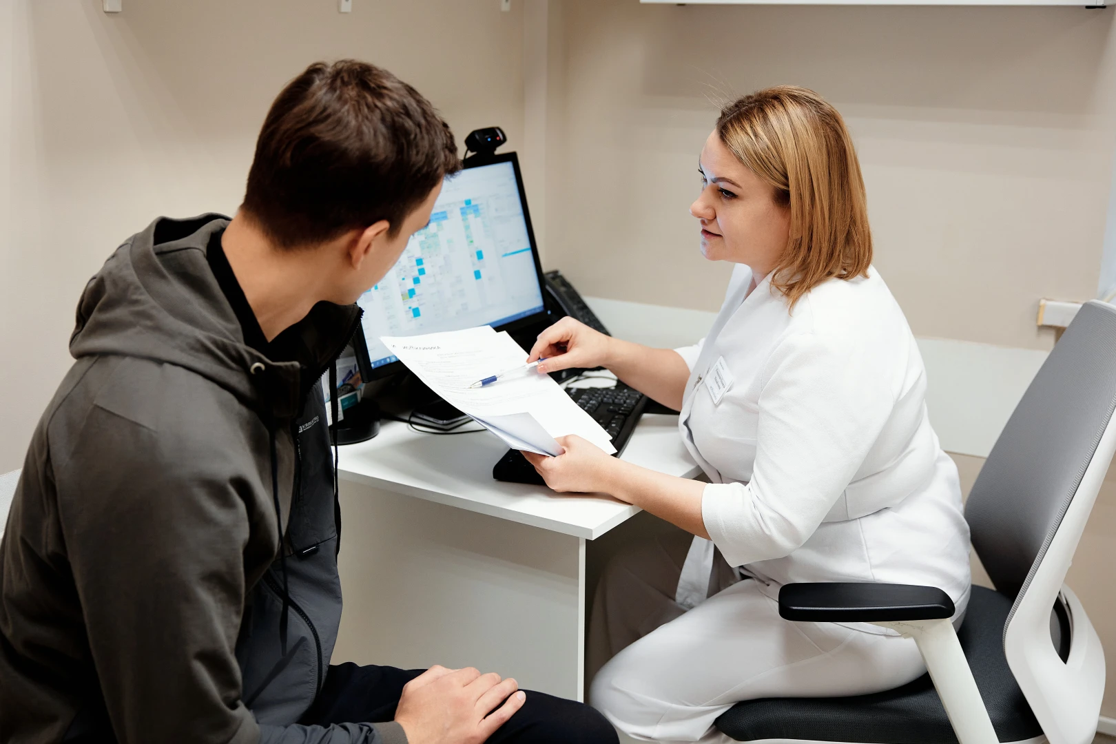 Врач-травматолог проводит осмотр и консультацию пациента перед процедурой