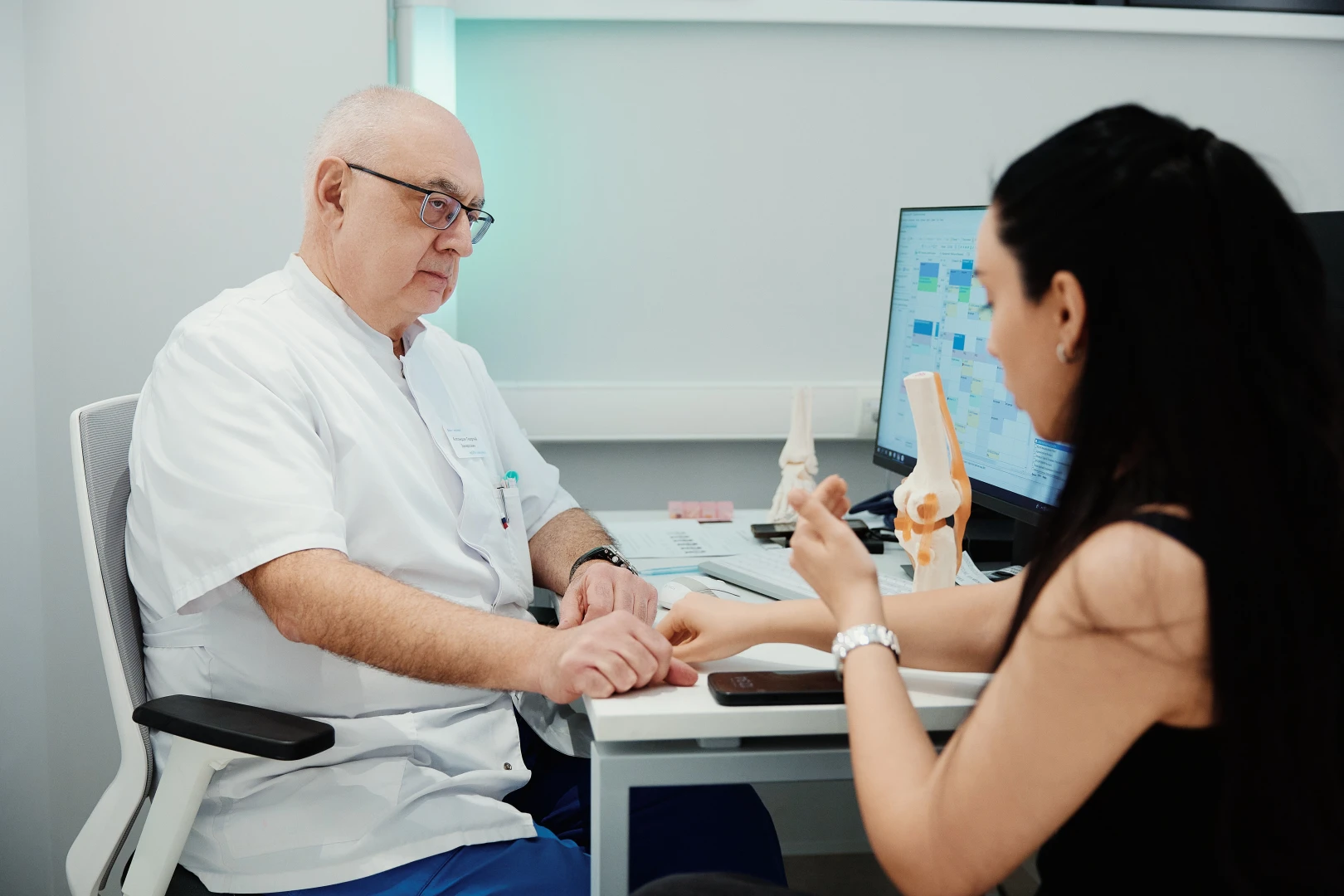 Травматолог-ортопед беседует с пациентом перед проведением пункции лучезапястного сустава