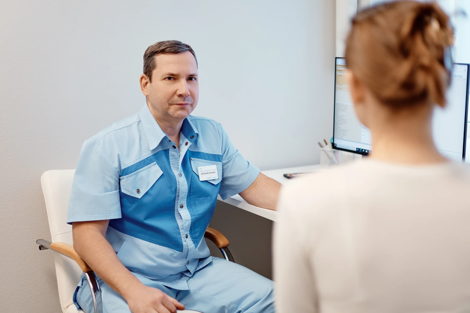 Мужчина врач в белом халате делает УЗИ сосудов печени пациенту.