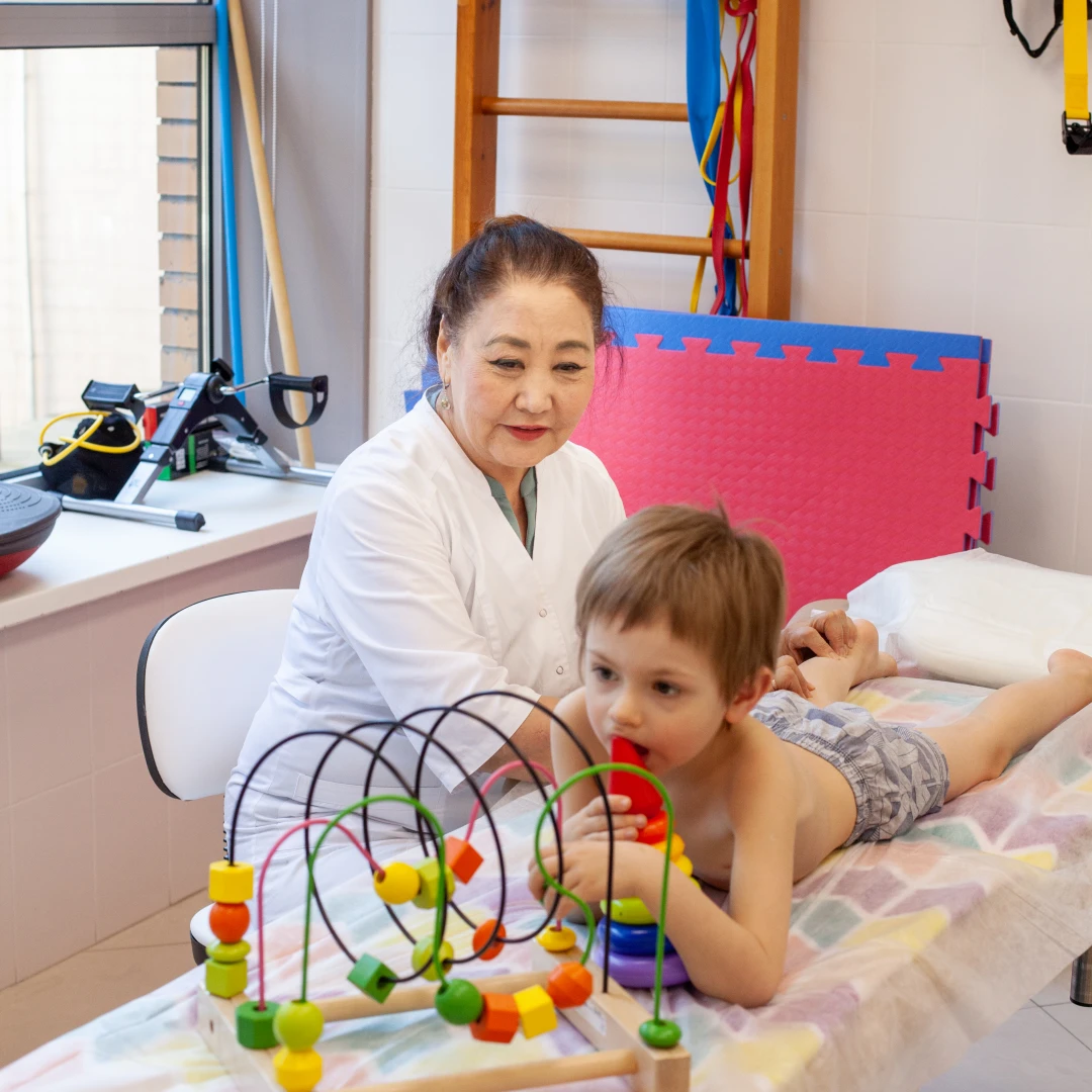 Специалист занимается с ребёнком лечебной физкультурой