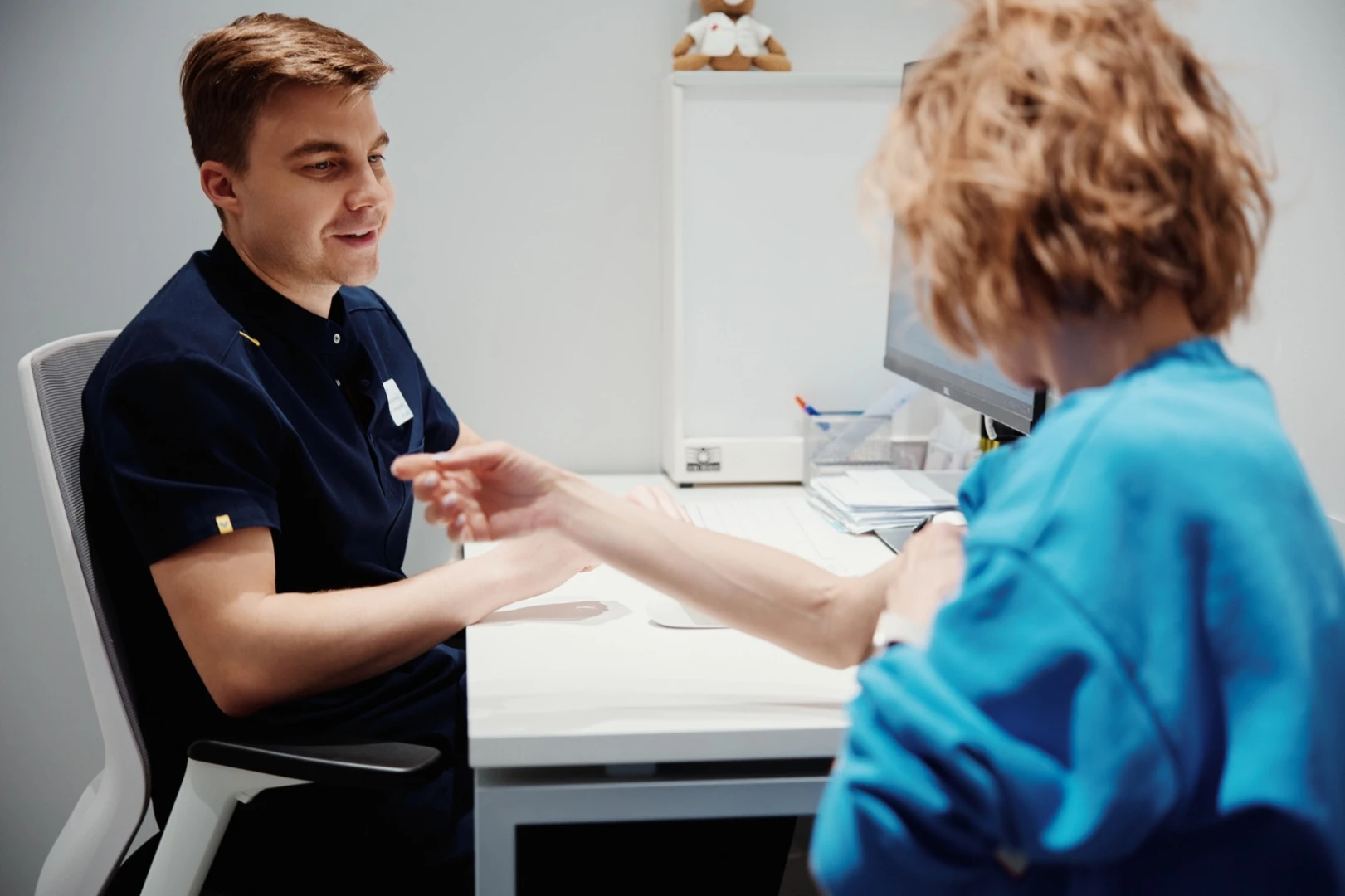 Специалист проверяет объём движений в руке пациентки на консультации